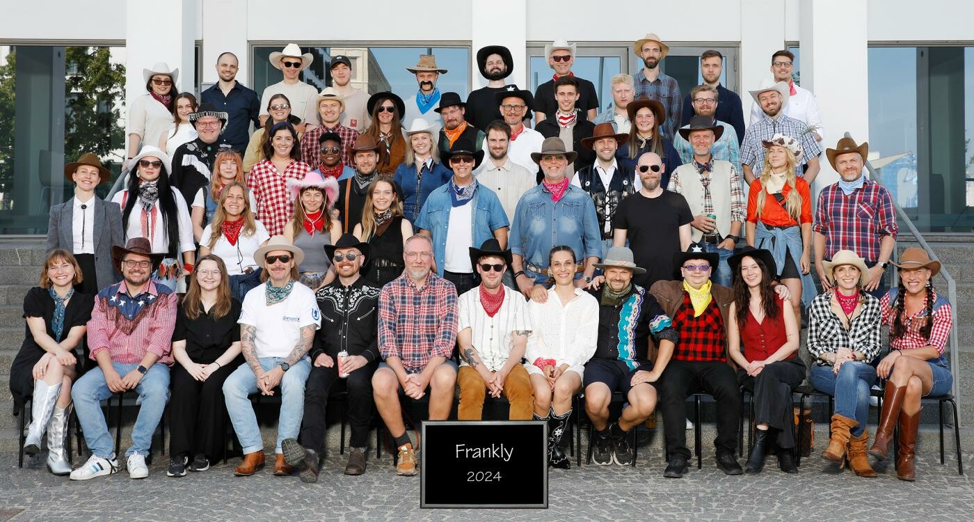 A class photo taken of all Frankly employees in front of a building